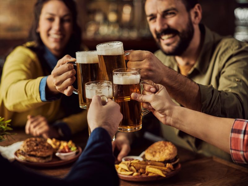 Close-up of friends toasting with beer in a pub.